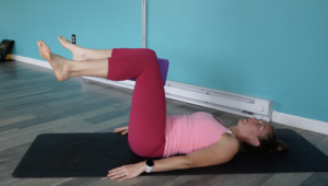 hip internal rotation strengthening exercise where Dr. Chloe is lying on her back with a yoga block inbetween her knees squeezing while internally rotating her legs